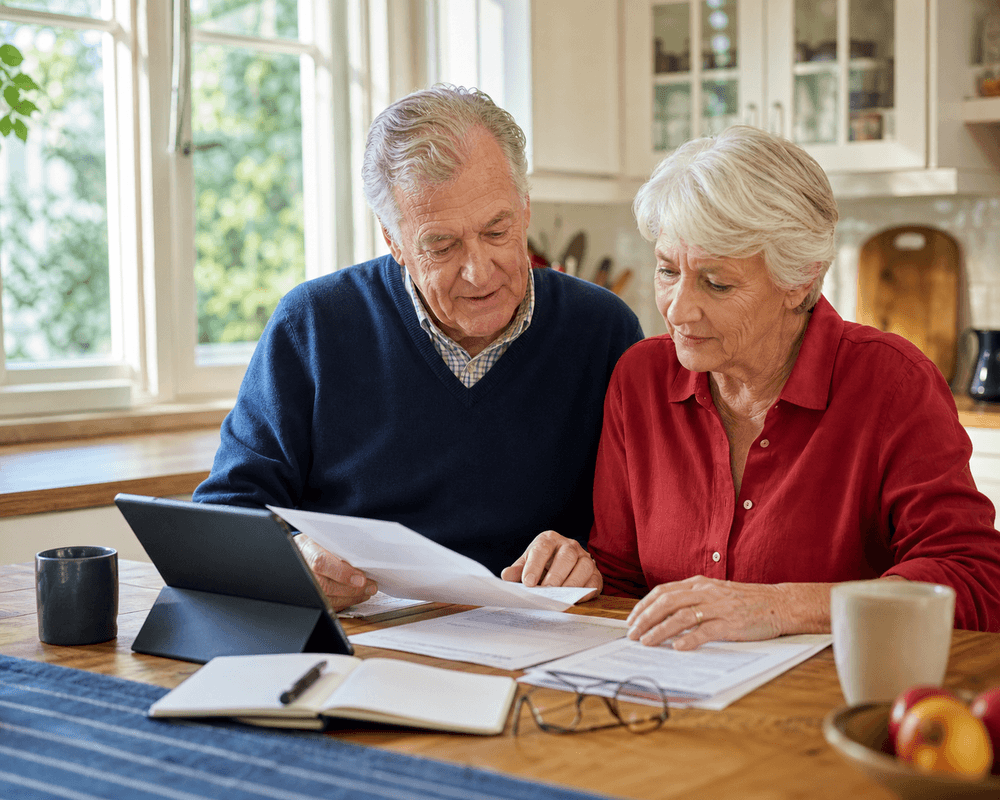 Senior couple reviewing household paperwork at a kitchen table